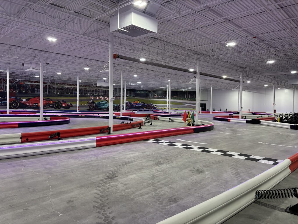 A large indoor racing track with lights and checkered flags.