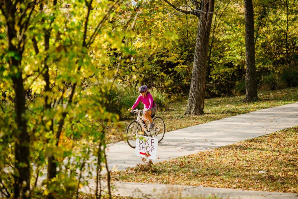a woman riding a bike down a path.