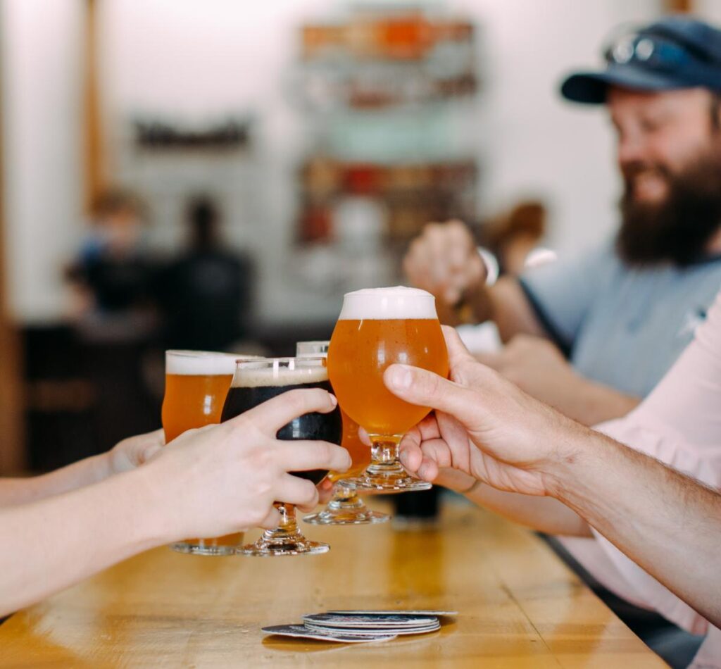 a group of people toasting beer glasses at a bar.