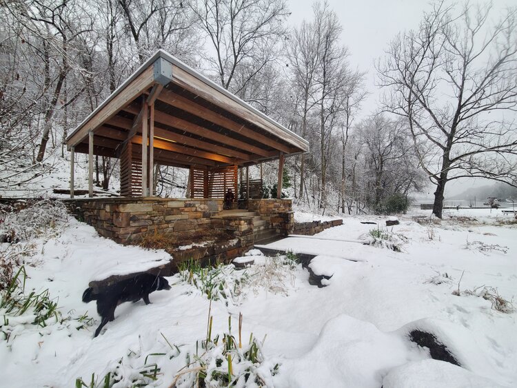 A wooden gazebo sits on top of a snow covered hill.