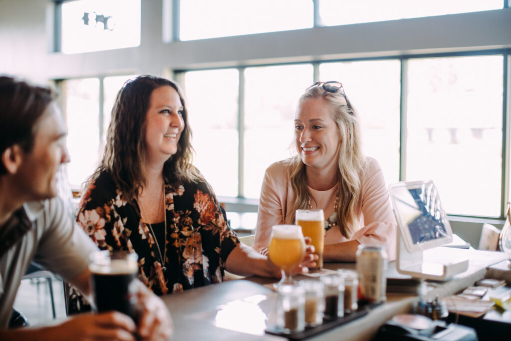 a group of people sitting at a bar and drinking beer.