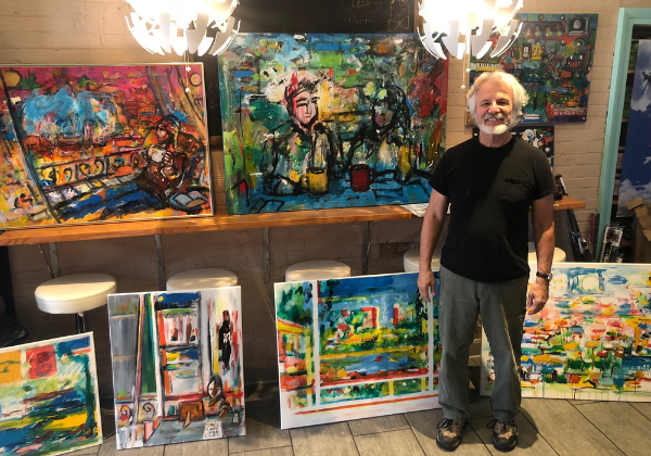 a man standing in front of a group of paintings.