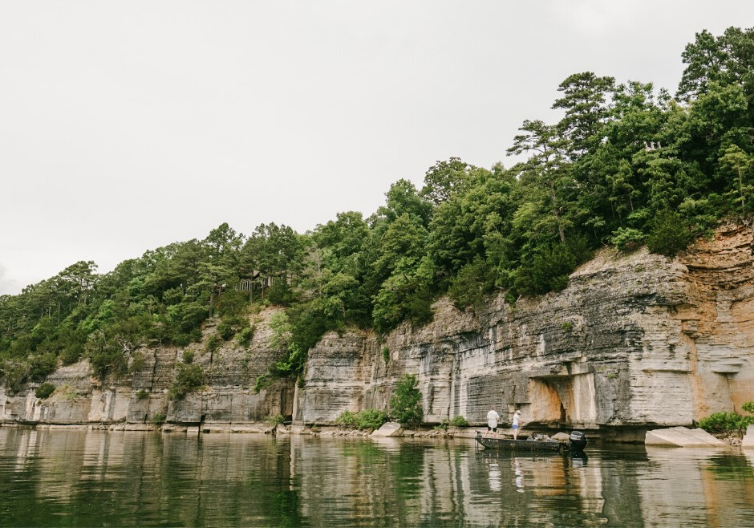a boat on the water next to a cliff.