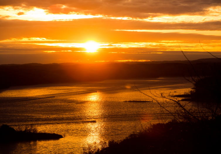 the sun is setting over a body of water.