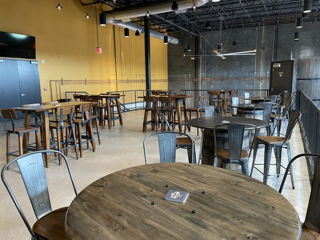 the inside of a brewery with tables and chairs.