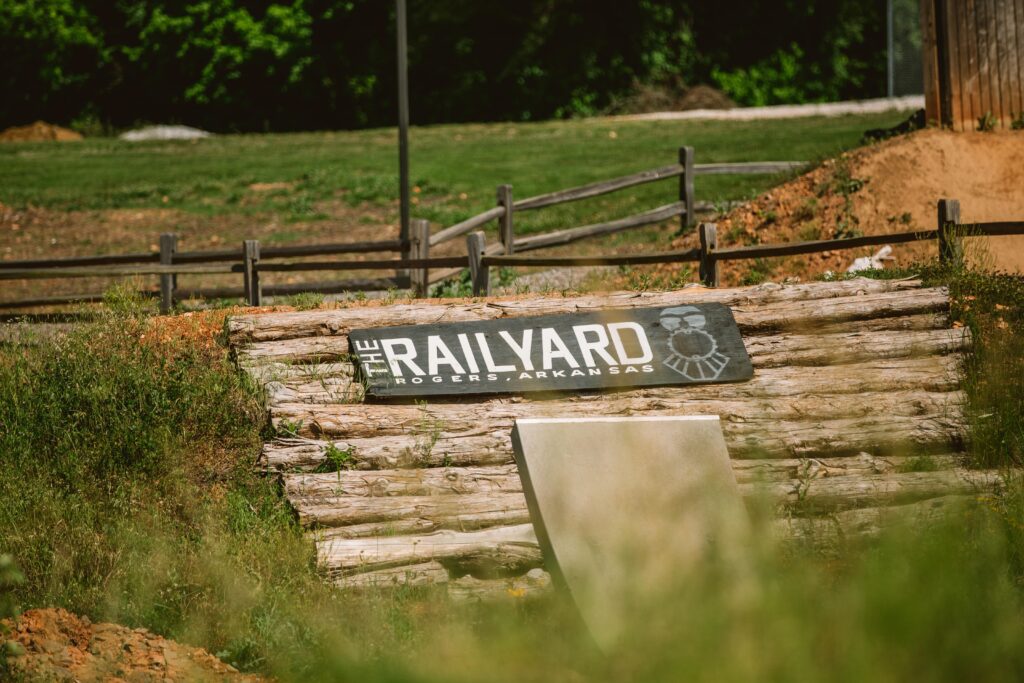 the railroad sign in front of a grassy field.