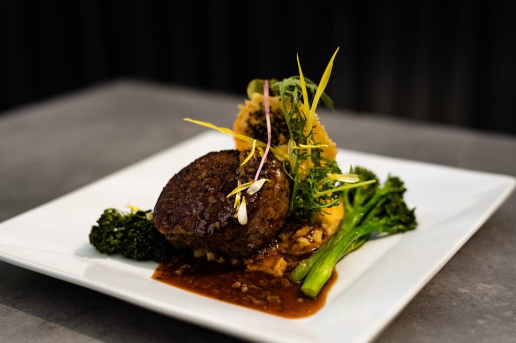 a plate of meat and broccoli on a table.