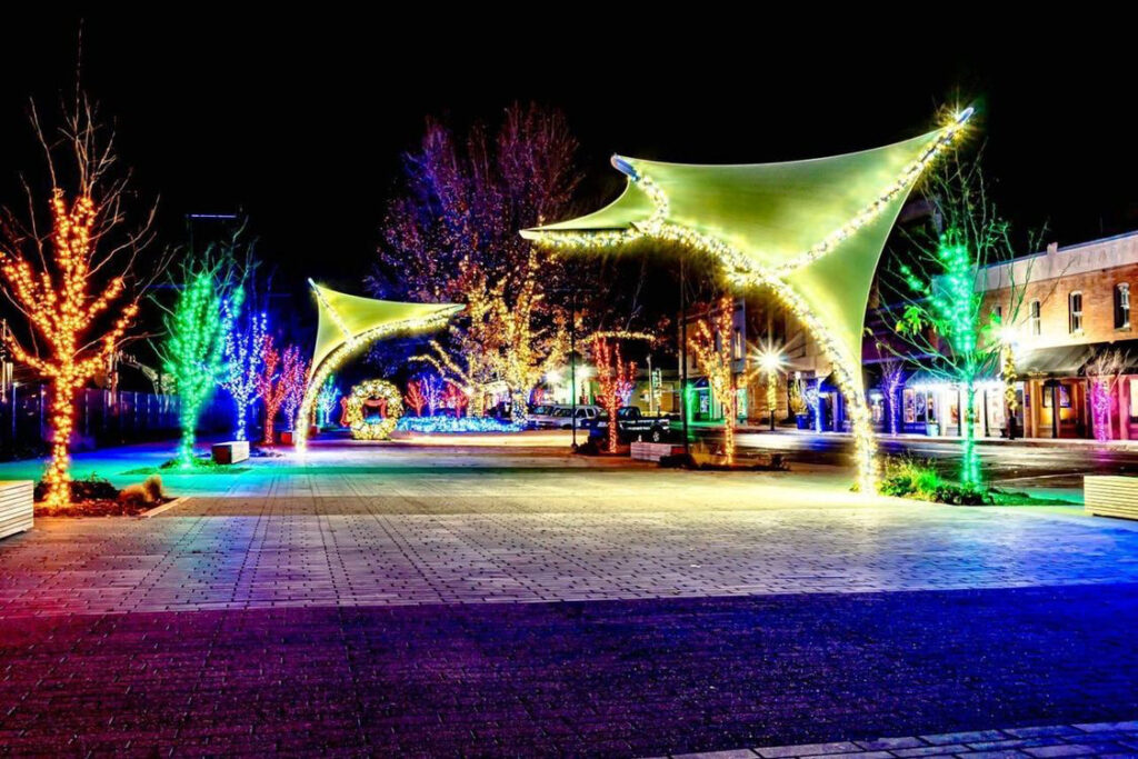 A town square lit up at night with colorful lights.