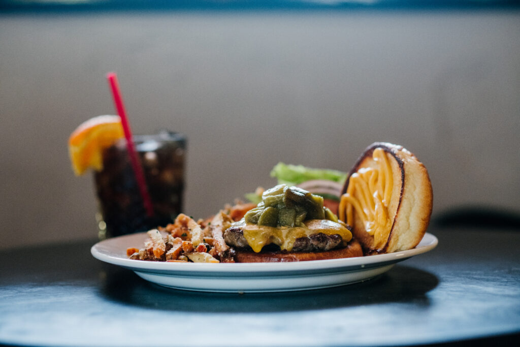 A plate with a burger and a drink on it.