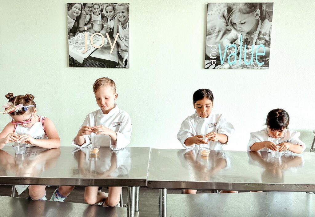A group of children sitting at a table in a kitchen.