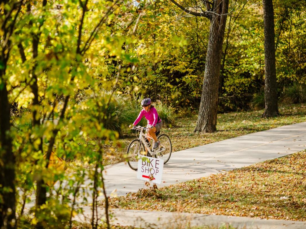 a woman riding a bike down a path.