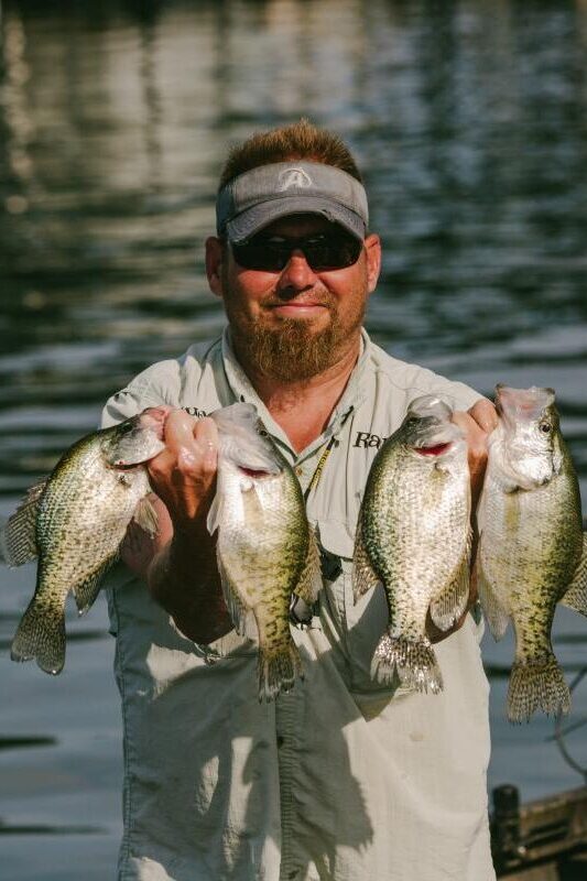a man holding up two small fish on a boat.