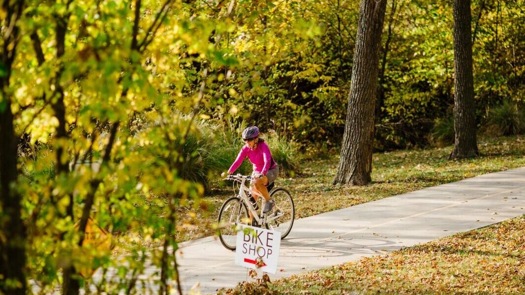a woman riding a bike down a path.