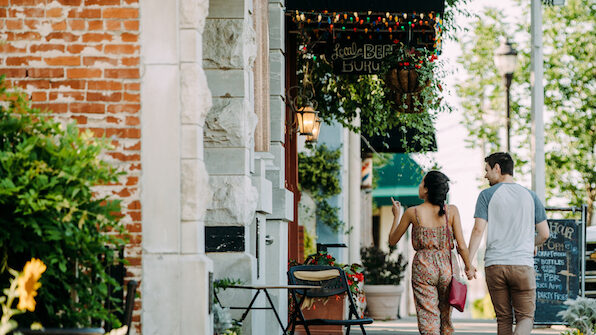 a couple walking down a sidewalk in a small town.