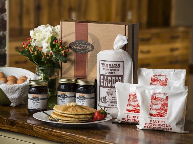 a box of pancakes, eggs, and other food sits on a table.