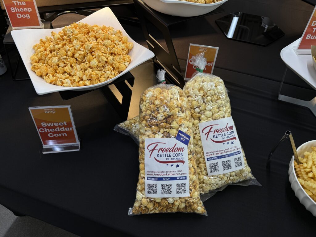 Bags of Freedom Kettle Corn and a bowl of Sweet Cheddar Corn are displayed on a table with labels.