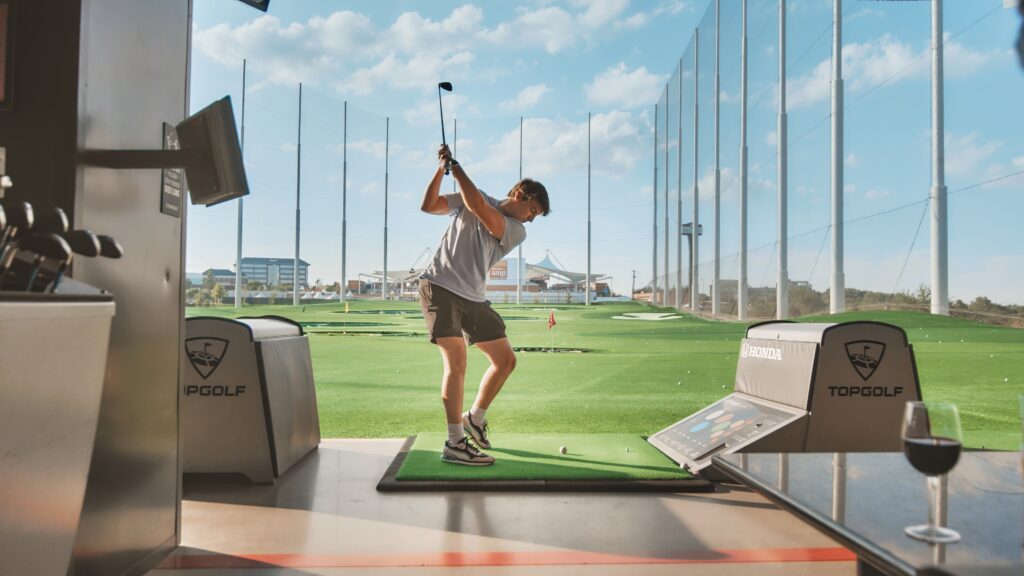 Man swinging a golf club at top golf