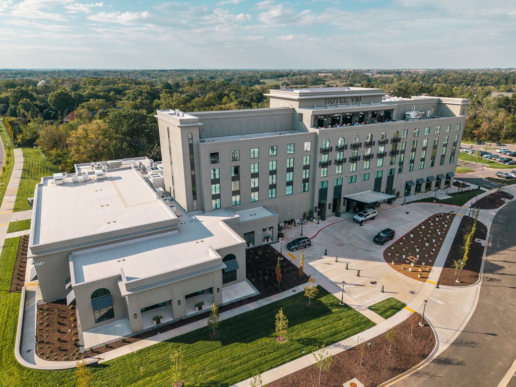 Aerial view of Hotel Vin, a multistory hotel building with an attached event space, surrounding parking, and landscaping.